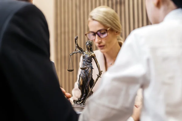 Statue de la Justice avec sa balance et son épée posée sur une table lors d'une réunion professionnelle.