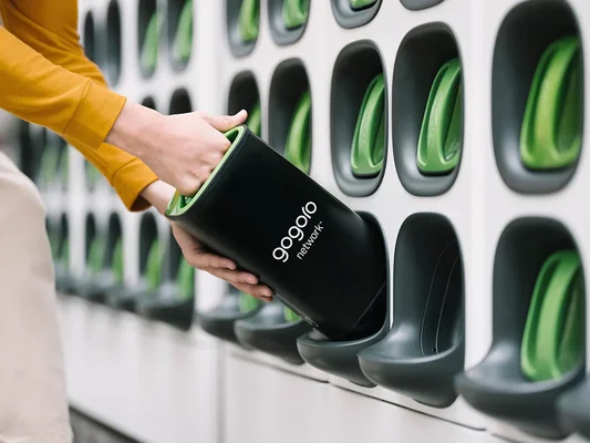 Une personne insère une batterie intelligente Gogoro dans une station de recharge murale.