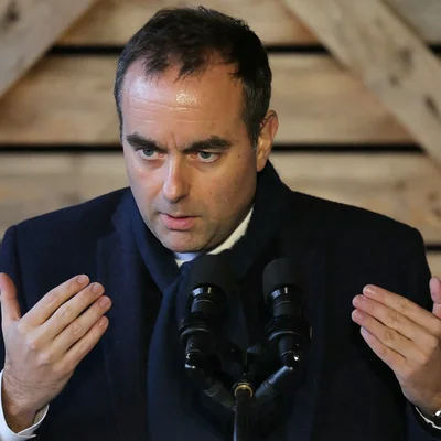 Sébastien Lecornu à un tribune avec micros, gestuant de la main.