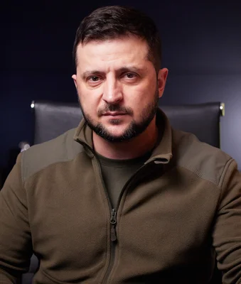 Le président ukrainien Volodymyr Zelenskyy en avril 2022, arborant une barbe et un pulls en polaire brun sur fond sombre.