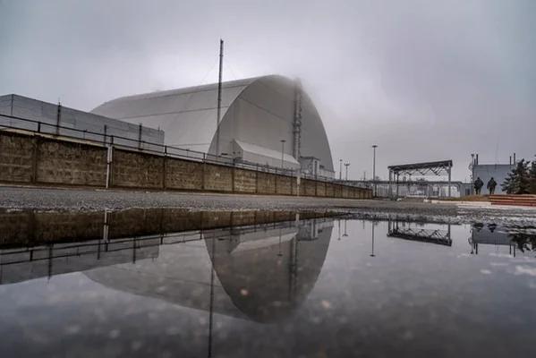 L'arche de Tchernobyl reflétée dans une flaque par jour de brouillard.