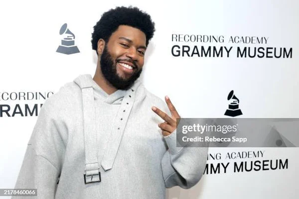 Khalid posant avec un signe de paix devant le logo du Grammy Museum.