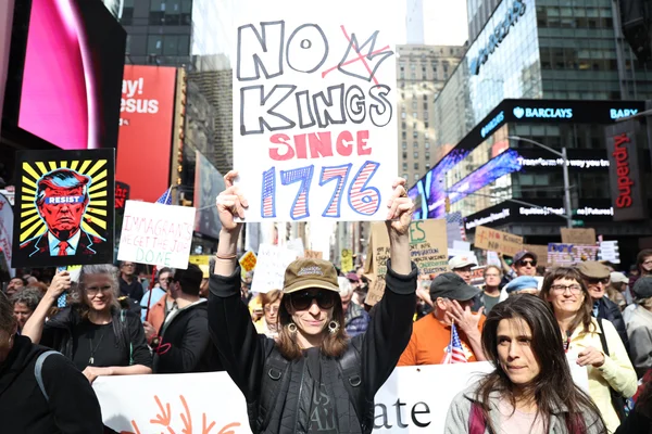 Un manifestant lève une pancarte « NO KINGS SINCE 1776» lors du « No Kings Day» au milieu d'autres protestataires.