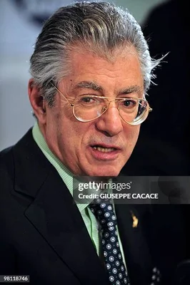 Umberto Bossi en costume sombre et chemise verte.