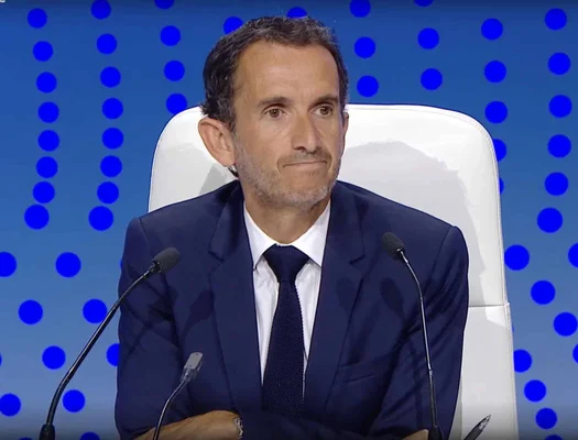 Alexandre Bompard assis face à des micros