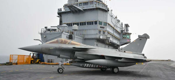 Un Rafale de la Marine française garé sur le pont d'envol d'un porte-avions par temps nuageux.