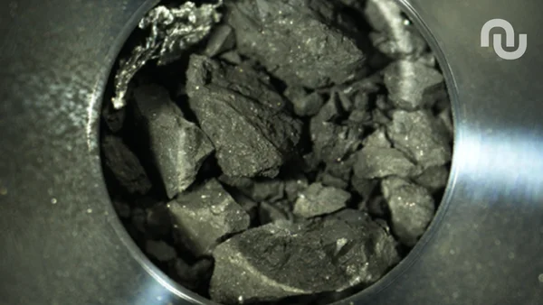 Fragments de l'astéroïde Ryugu visibles à travers une ouverture métallique.