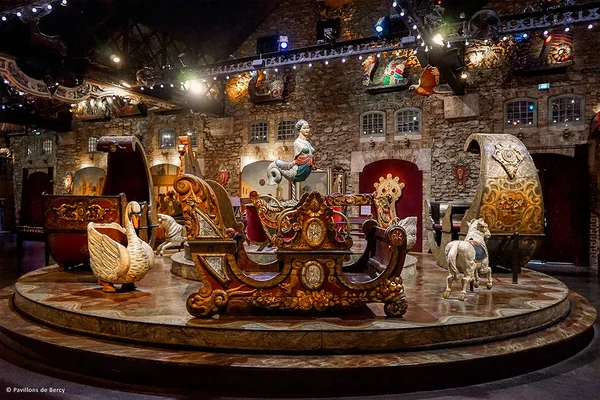 Manège Belle Époque aux calèches dorées et aux figures de chevaux, installé dans les pavillons en pierre du musée.