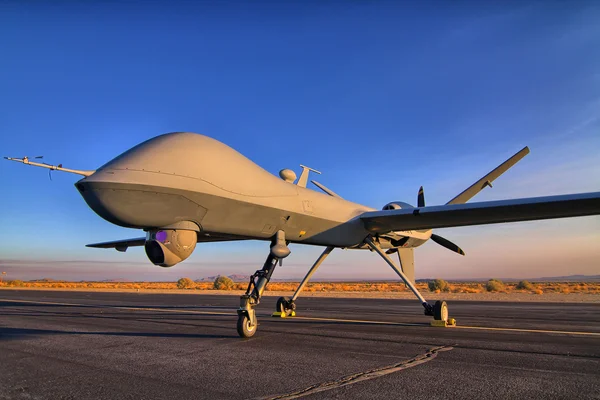 Un drone MQ-9A Reaper stationné sur une piste avec un fond de ciel bleu.