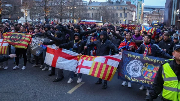 Supporters massés dans une ville arborant des drapeaux et bannières, dont ceux du FC Barcelone.