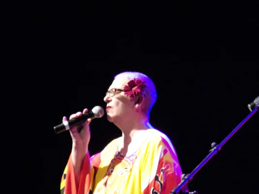 Desireless lors d'un concert à Sorgues en 2016, coiffée d'une fleur rouge et vêtue d'un habit coloré.