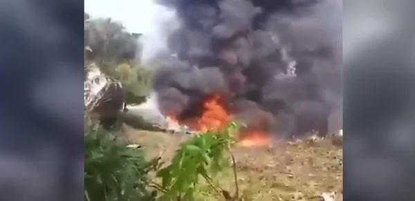 Un incendie avec épaisse fumée noire s'élevant d'une zone herbeuse.