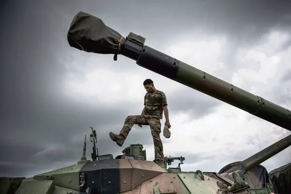 Militaire français en position sur le canon d'un véhicule blindé sous un ciel couvert.