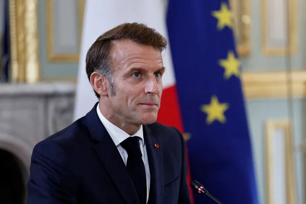 Emmanuel Macron devant des drapeaux français et européens.