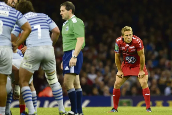 Moment de pause ou de blessure pour un joueur en maillot rouge au milieu du terrain.