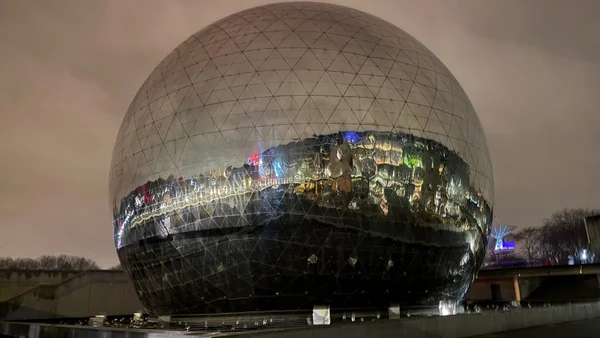 Le dôme géodésique de La Géode illuminé la nuit.