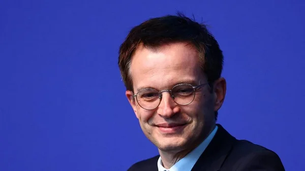 Édouard Philippe souriant, en costume et lunettes rondes.