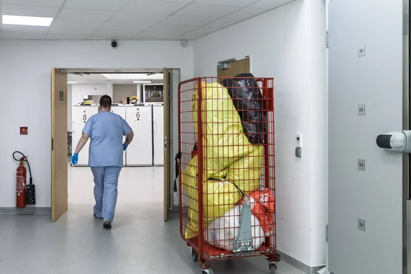 Intérieur d'une morgue hospitalière avec des unités de stockage numérotées et un chariot de transport dans un couloir clinique.
