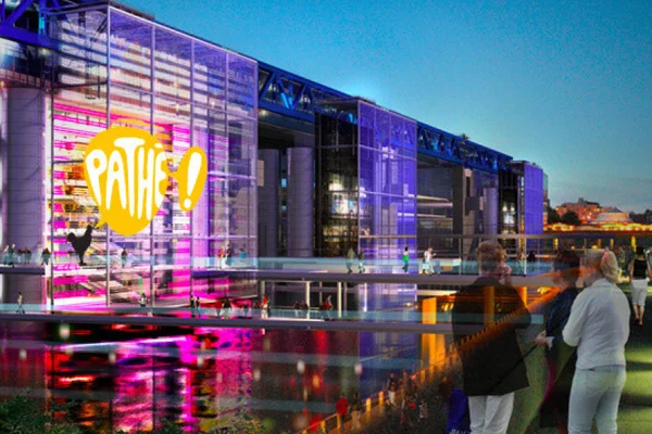 Façade du cinéma Pathé La Villette illuminée aux couleurs roses et violettes, la nuit.
