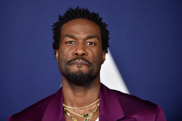Yahya Abdul-Mateen II portant une veste violette et des colliers en or.