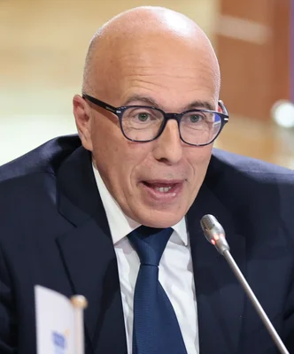 Éric Ciotti discutant avec un collaborateur lors d'un événement officiel extérieur.