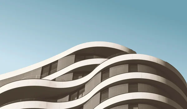 Bâtiment moderne aux lignes ondulantes sous le ciel.