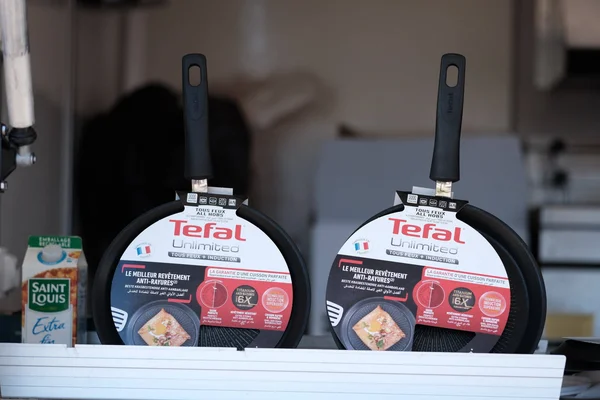 Deux poêles Tefal Unlimited avec manches noirs et emballage exposés sur une étagère blanche.