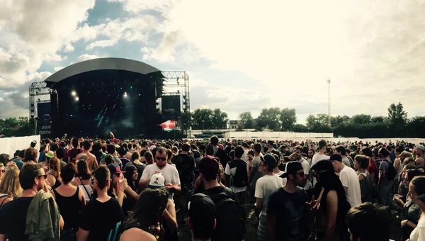 Une grande foule rassemblée devant la scène du Dour Festival sous un ciel partiellement nuageux.
