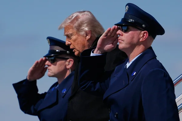 Le président Donald Trump salue entre deux militaires en uniforme lors d'un transfert solennel à la base de Dover.