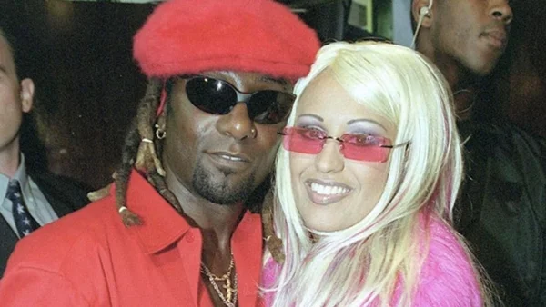 Lââm en chapeau et veste rouges posant avec un proche lors d'un événement public.