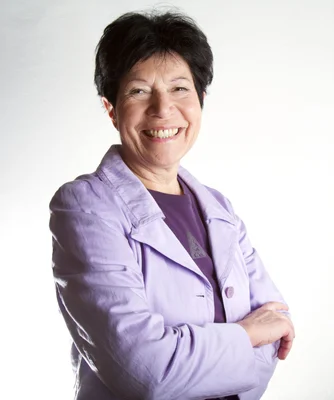 Helga Nowotny bras croisés, portant une veste violette sur un fond blanc.