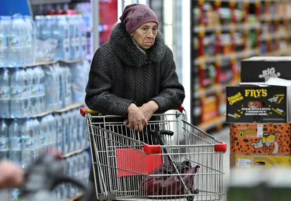 Une femme âgée poussant un chariot dans un supermarché en Russie.
