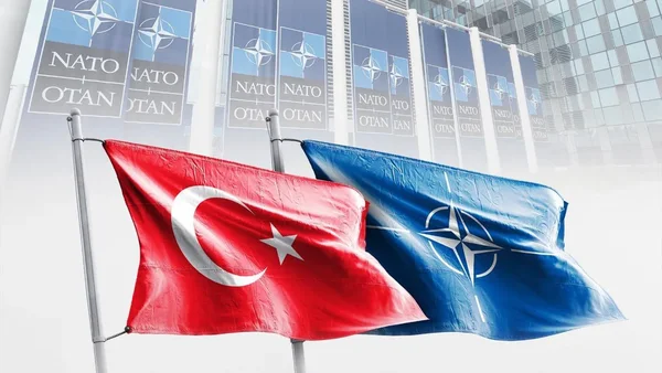 Les drapeaux de la Turquie et de l'OTAN flottant devant un bâtiment aux couleurs de l'alliance.