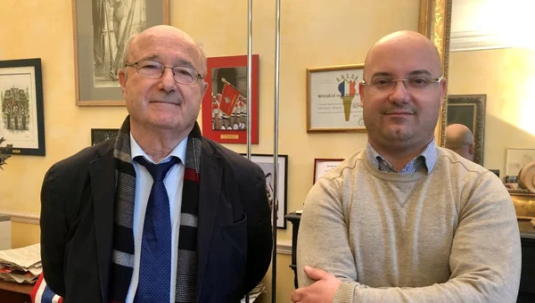 Yann Bompard debout aux côtés d'un homme en costume bleu.