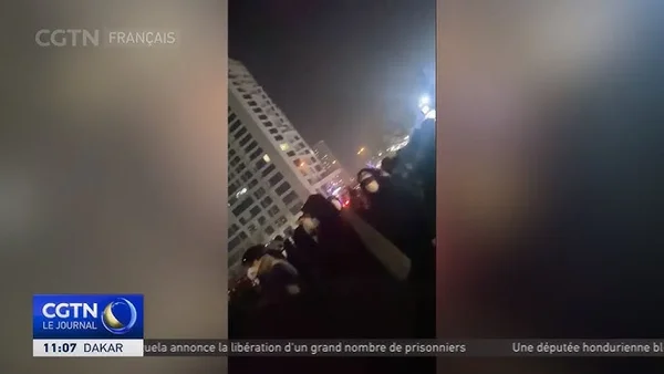 Vue nocturne depuis un toit avec lumières de la ville et information CGTN Français.