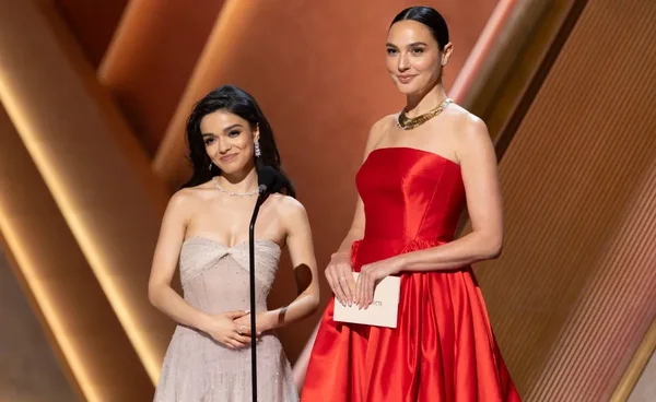 Deux actrices en robes de soirée rouge et gris se tenant sur scène lors d'un événement promotionnel.
