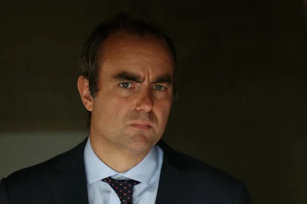 Sébastien Lecornu en costume et chemise bleu clair sur fond sombre.