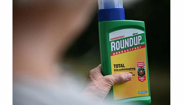 Une bouteille de concentré Roundup tenue en main, montrant l'étiquetage allemand.