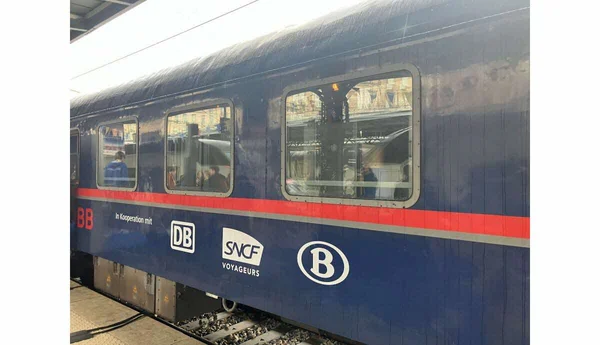 Une voiture du train de nuit Paris-Berlin affichant les logos DB et SNCF Voyageurs sur le quai d'une gare.