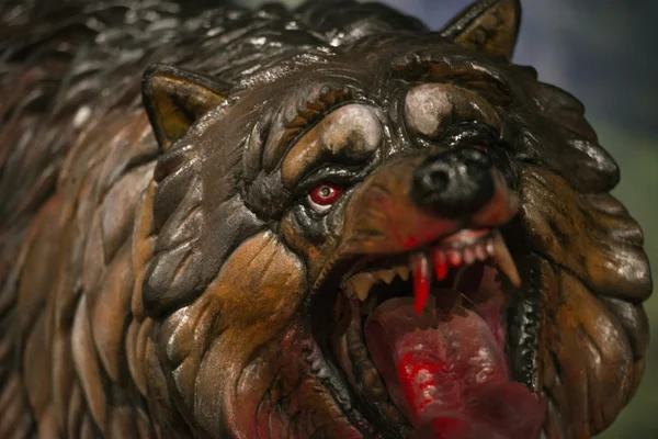 Gros plan d'une figurine de loup ou loup-garou menaçant, aux yeux rouges et à la fourrure texturée.