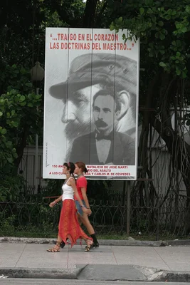 Deux femmes marchent devant une affiche montrant Fidel Castro et José Martí à La Havane.