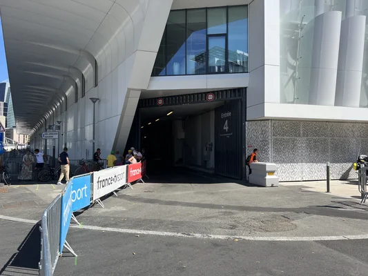 L'entrée n°4 de la Paris la Défense Arena à Nanterre, avec des barrières de signalisation et des spectateurs attendant devant le bâtiment.