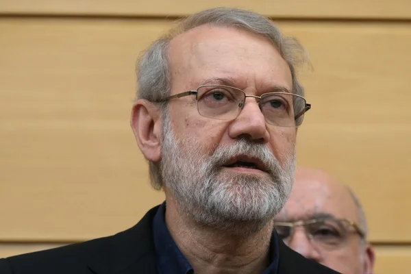 Ali Larijani en blazer sombre et chemise bleue lors d'un événement officiel.