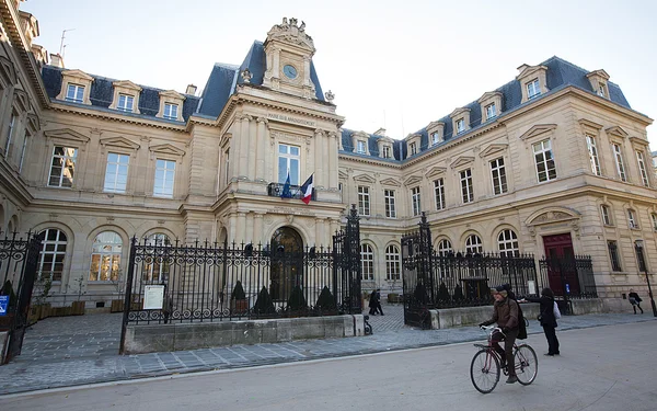 La place de l'Hôtel de Ville de Paris avec son bâtiment historique, ses grilles en fer et la circulation.