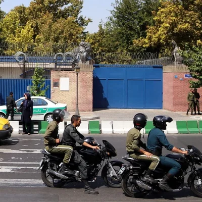 Des motards en uniforme patrouillent près d'une bâtiment sécurisé.