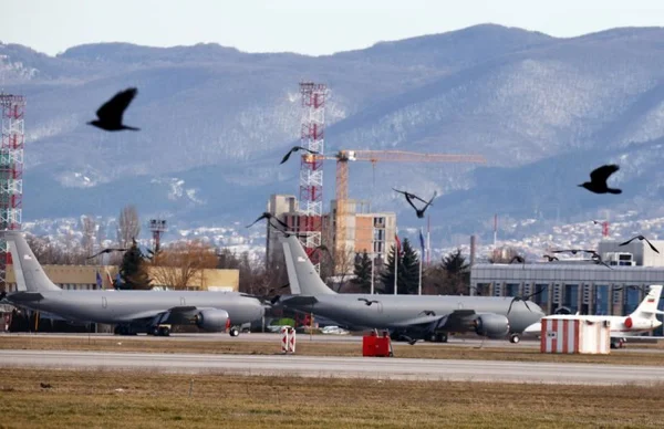Deux avions militaires gris sur le tarmac de l'aéroport de Sofia avec des montagnes en arrière-plan
