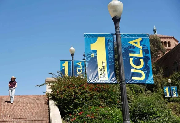 Vue ensoleillée du campus de l'UCLA avec des bannières bleues et une personne descendant des escaliers.