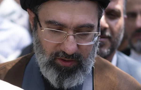 Mojtaba Khamenei assis dans un officiel, devant une carte, portant son costume traditionnel et son turban noir.