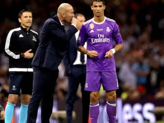 Zinédine Zidane donnant des consignes à un joueur du Real Madrid sur le terrain.