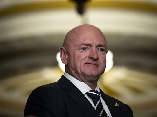 Le sénateur Mark Kelly en costume cravate sur fond éclairé.